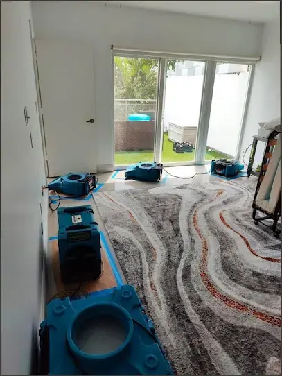 Living room with air movers and dehumidifiers drying the carpet in Pico Rivera, CA