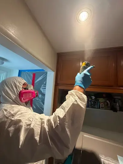 Tech in a protective suit and respirator treating kitchen cabinets during a water loss in Pico Rivera, CA