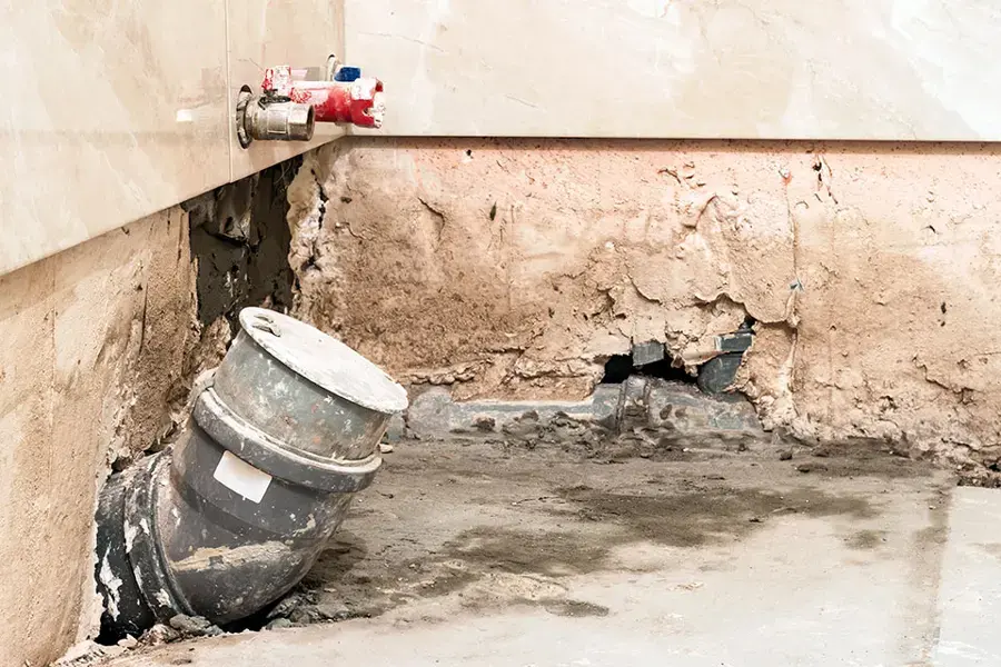 Wall opened at the base to expose the drain pipe behind a leak in Pico Rivera, CA