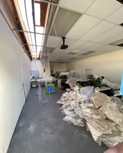 Office with ceiling tiles pulled down and wet debris bagged on the floor in Pico Rivera, CA