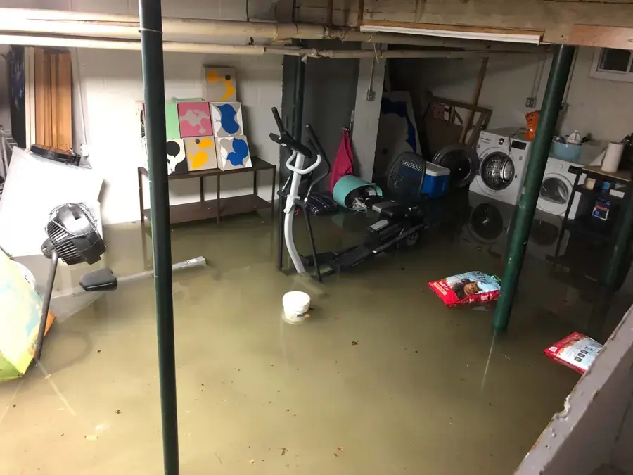Garage flooded with storm water around stored furniture and an exercise bike in Pico Rivera, CA
